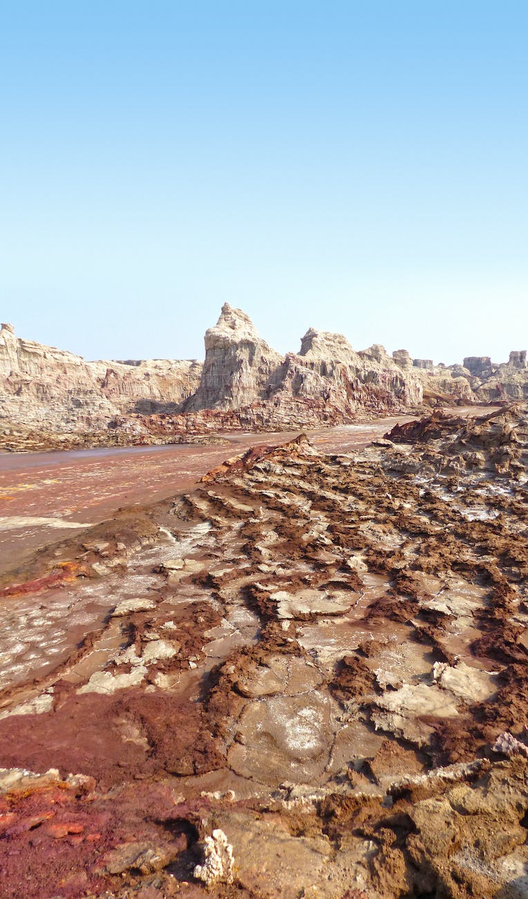 brown field near rocky mountains under blue sky